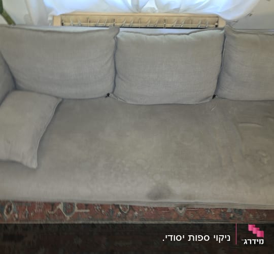 ספת בד אפורה בעלת שלושה מושבים ואיזור מוכתם לפני ניקוי